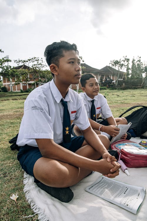 Students in School Uniforms Sitting on Picnic Blanket