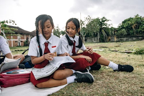Two Female Students Sitting on the Field