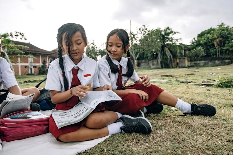 Two Female Students Sitting On The Field