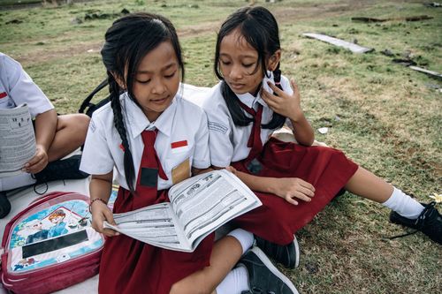 Free Two young students in school uniforms reading outdoors on a sunny day. Stock Photo