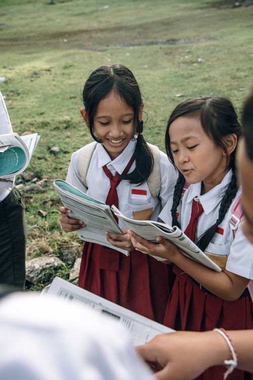 Free Two smiling children in school uniforms reading books outdoors, enjoying learning together. Stock Photo