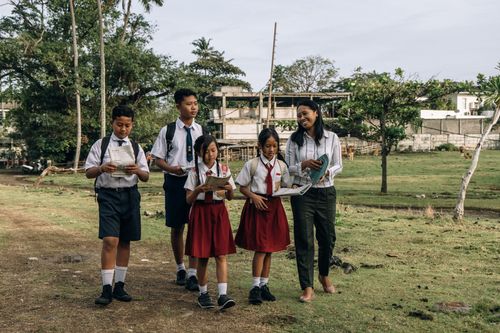 Free Group of students in uniforms, walking with their teacher in a rural setting. Stock Photo
