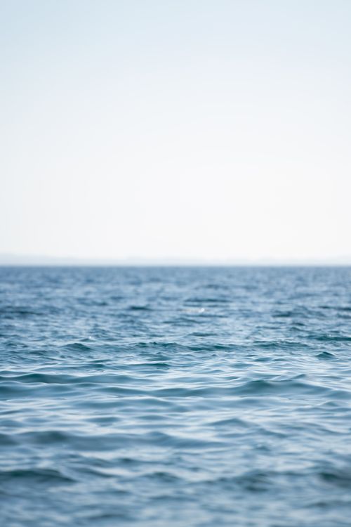 Free Peaceful ocean view with gentle waves and a bright, clear sky, perfect for relaxation imagery. Stock Photo