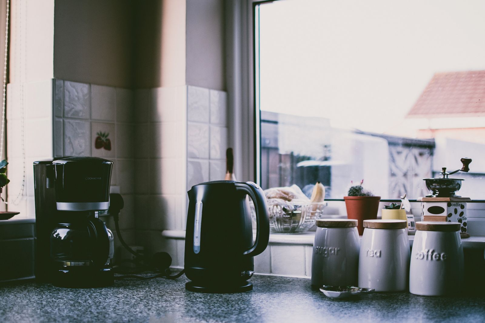 Coffee maker and electric kettle arranged on a warm kitchen counter