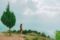 这张风景优美的照片中，一名女子在多云的天空下俯瞰郁郁葱葱的山坡，画面宁静祥和