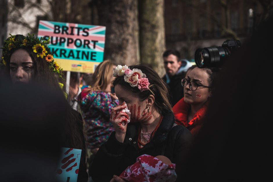 People rally in London to support Ukraine, expressing anti-war sentiments with signs and art makeup.
