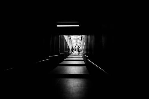 Grayscale Photo of People Walking on the Hallway