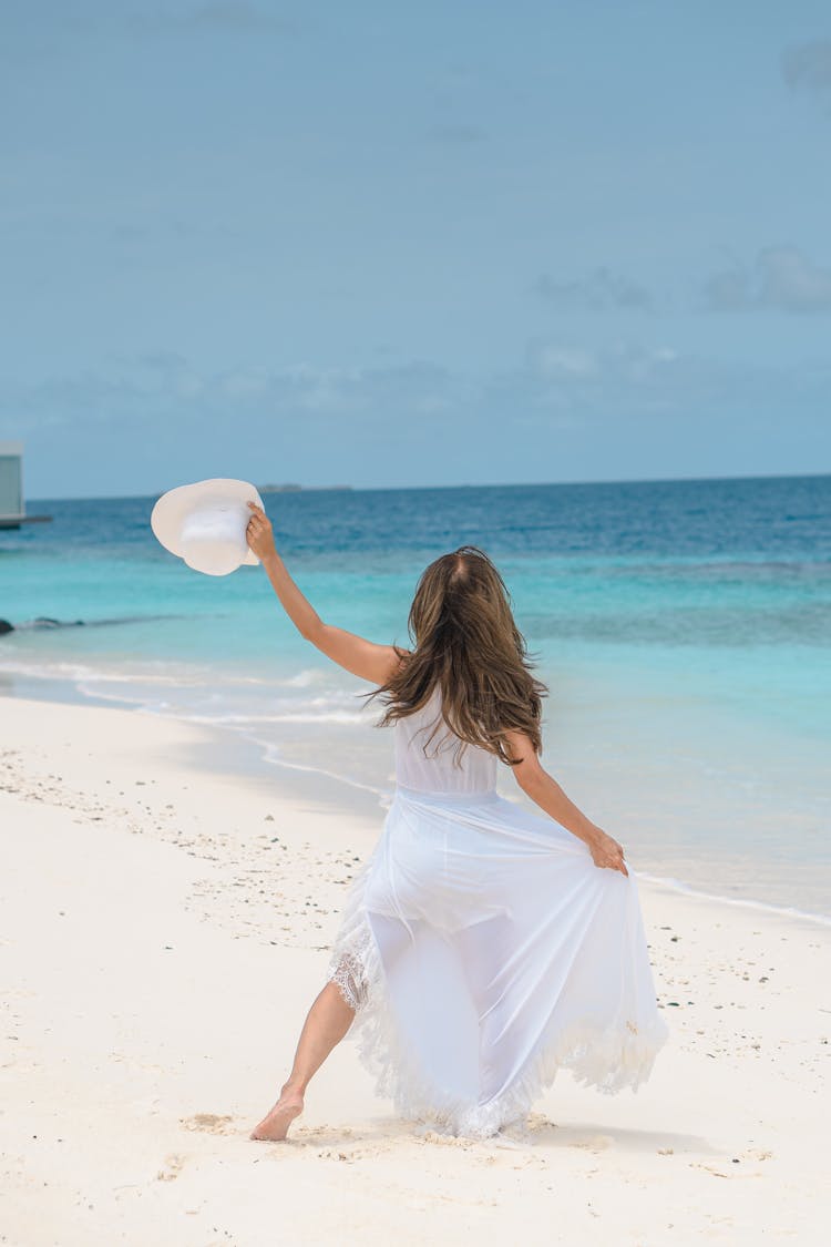 Woman In White Dress Walking On Beach