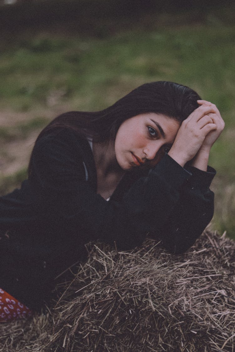 Woman Resting On Bale Of Hay