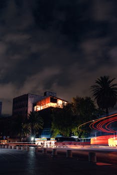 Vibrant city nightscape featuring light trails and illuminated buildings under a moody sky.