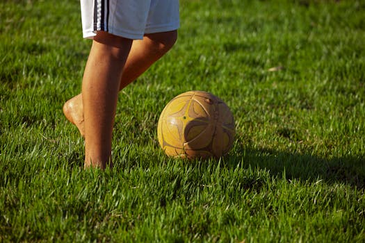 A young soccer player prepares to kick a ball on a lush grass field, perfect for sports enthusiasts.
