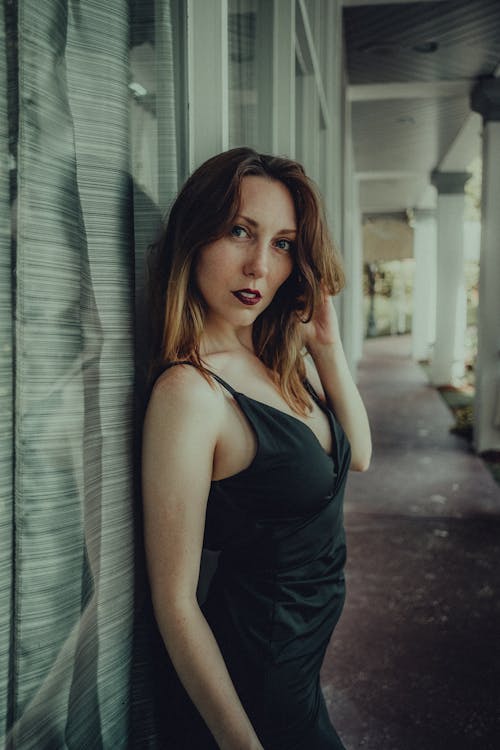  A Woman in Black Spaghetti Strap Dress Looking with a Serious Face