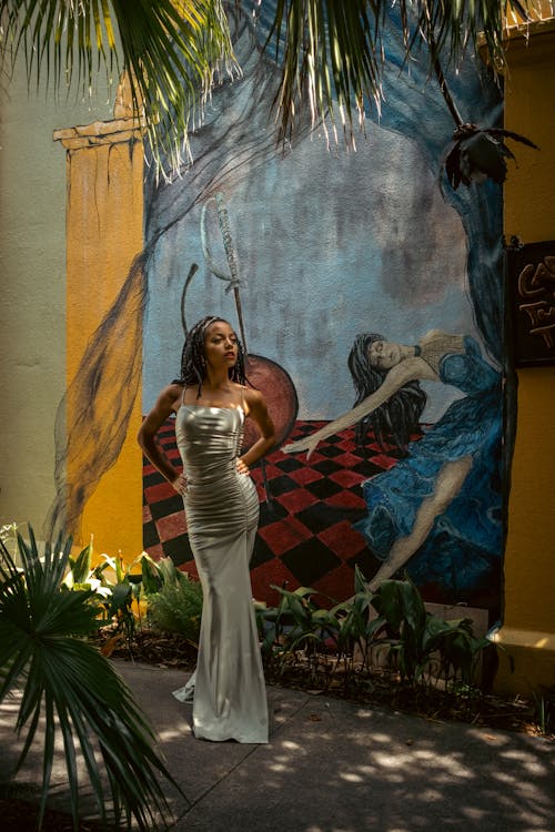 A Woman in a Gray Dress Standing beside a Mural