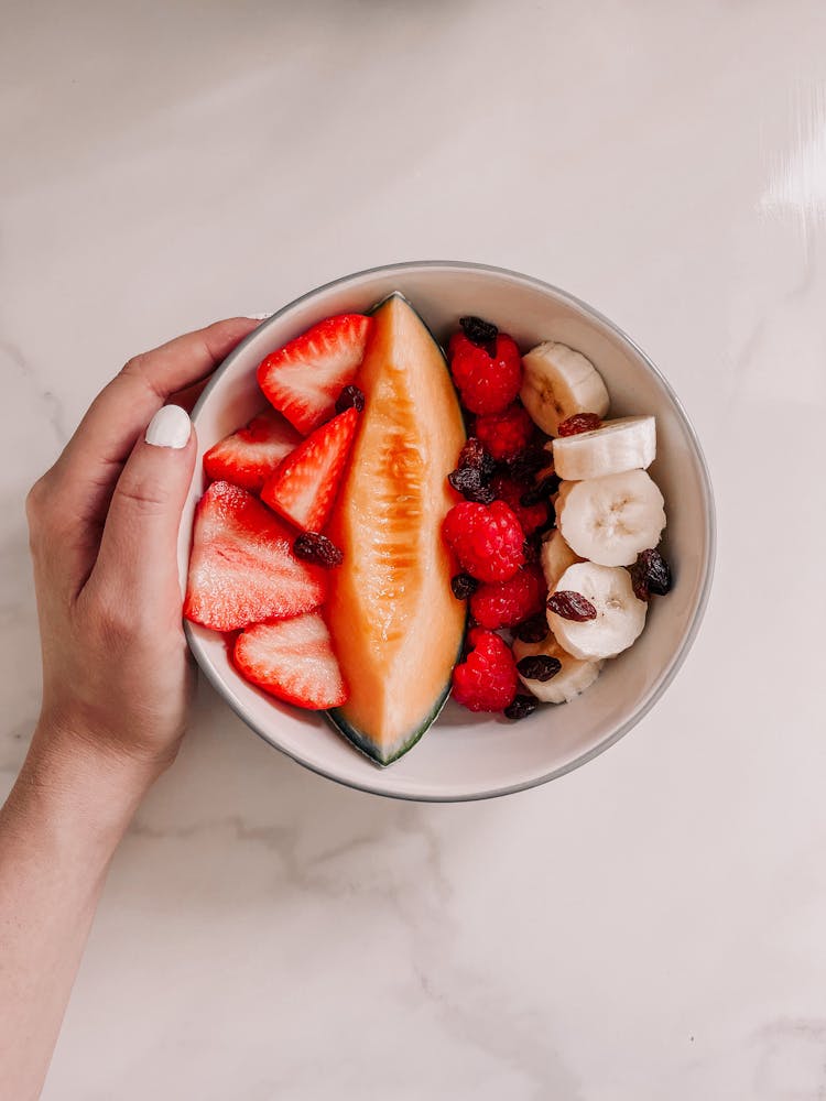 Hand Holding Bowl Of Fresh Fruits