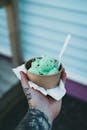 Person Holding Ice Cream Cone With Green Ice Cream