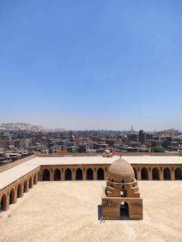 A breathtaking aerial view of the historic Ibn Tulun Mosque with the Cairo skyline.