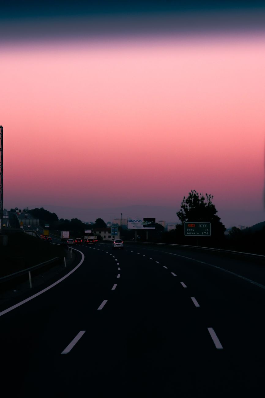 Beautiful highway scene at sunset with vibrant red and pink sky hues.