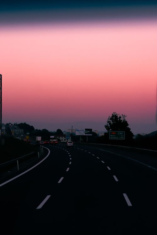 Free Beautiful highway scene at sunset with vibrant red and pink sky hues. Stock Photo