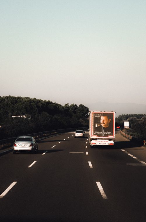 Free A clear scenic view of cars on a highway with trees and open sky during daytime. Stock Photo