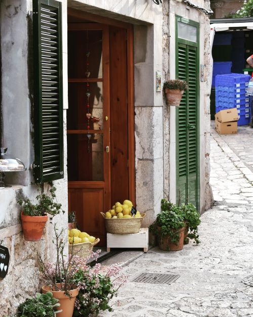 Free Rustic entrance with flowers and lemons on a Mediterranean street, evoking a warm, inviting atmosphere. Stock Photo