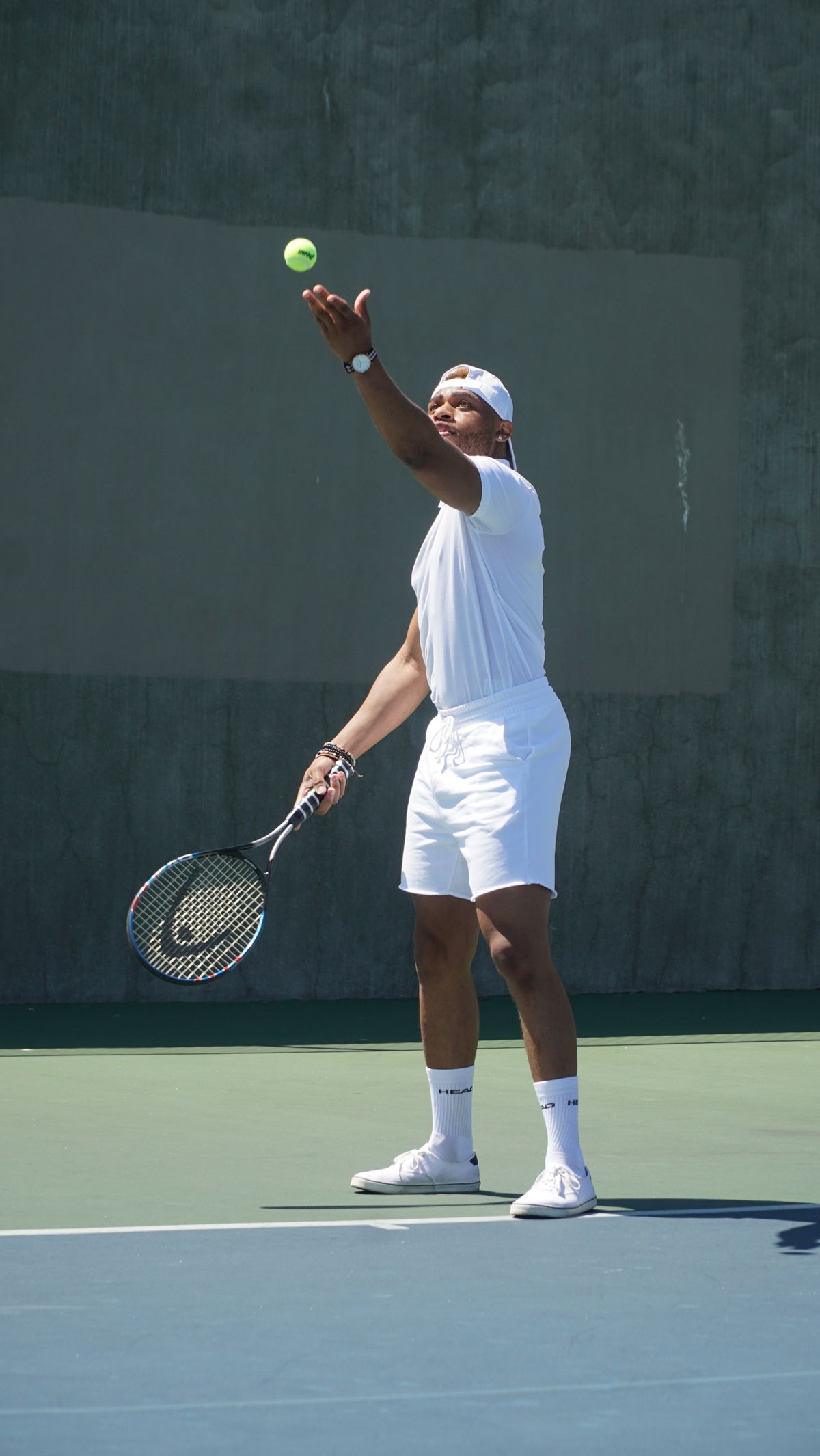Player tossing a ball to serve on a hard court