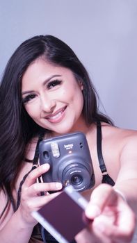 Young woman smiling and holding an instant camera with a photo.