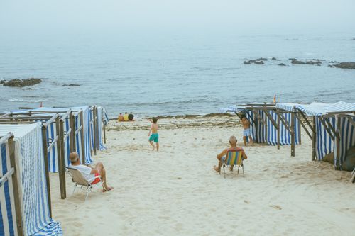 Free People enjoying a serene day at the beach with striped sun shelters and loungers by the sea. Stock Photo
