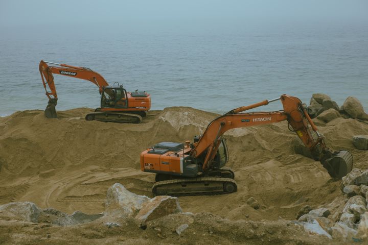Two excavators digging at a sandy site