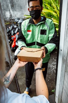 Delivery person hands packaged meal to customer at doorstep, ensuring safety.