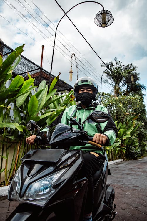 A Man in Green Jacket Riding a Black Motorcycle