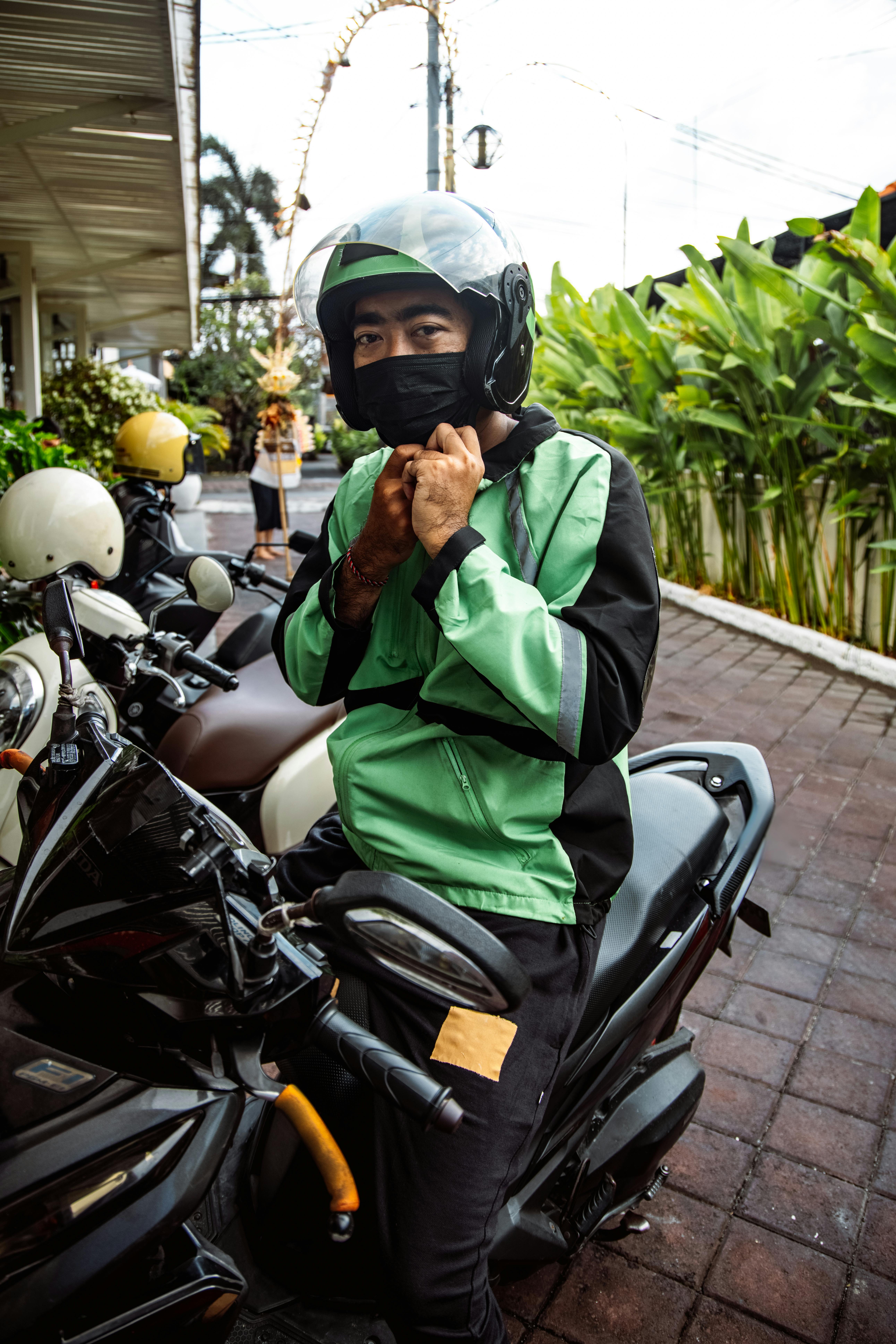 Motoboy ajustando capacete e mochila na moto