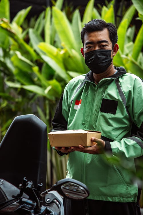 Delivery Man with Takeout Box Standing by Motorcy