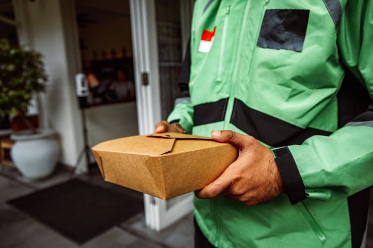 A Person In Green Jacket Holding A Box