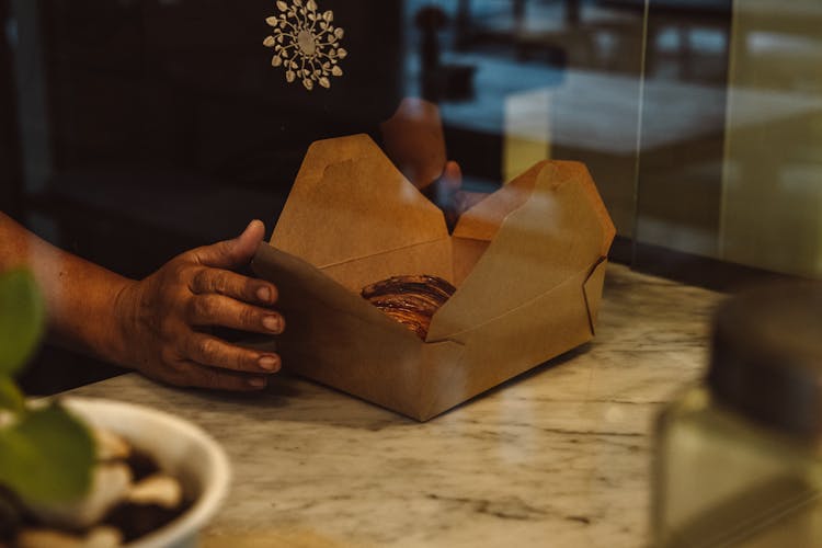 A Person Holding A Takeaway Box