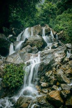 Captivating waterfall cascading over rocks amidst vibrant greenery, perfect for nature enthusiasts.