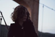 黄昏时分，老桥下一位卷发女子的剪影，捕捉到一种沉思的心情