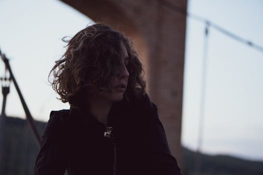 黄昏时分，老桥下一位卷发女子的剪影，捕捉到一种沉思的心情