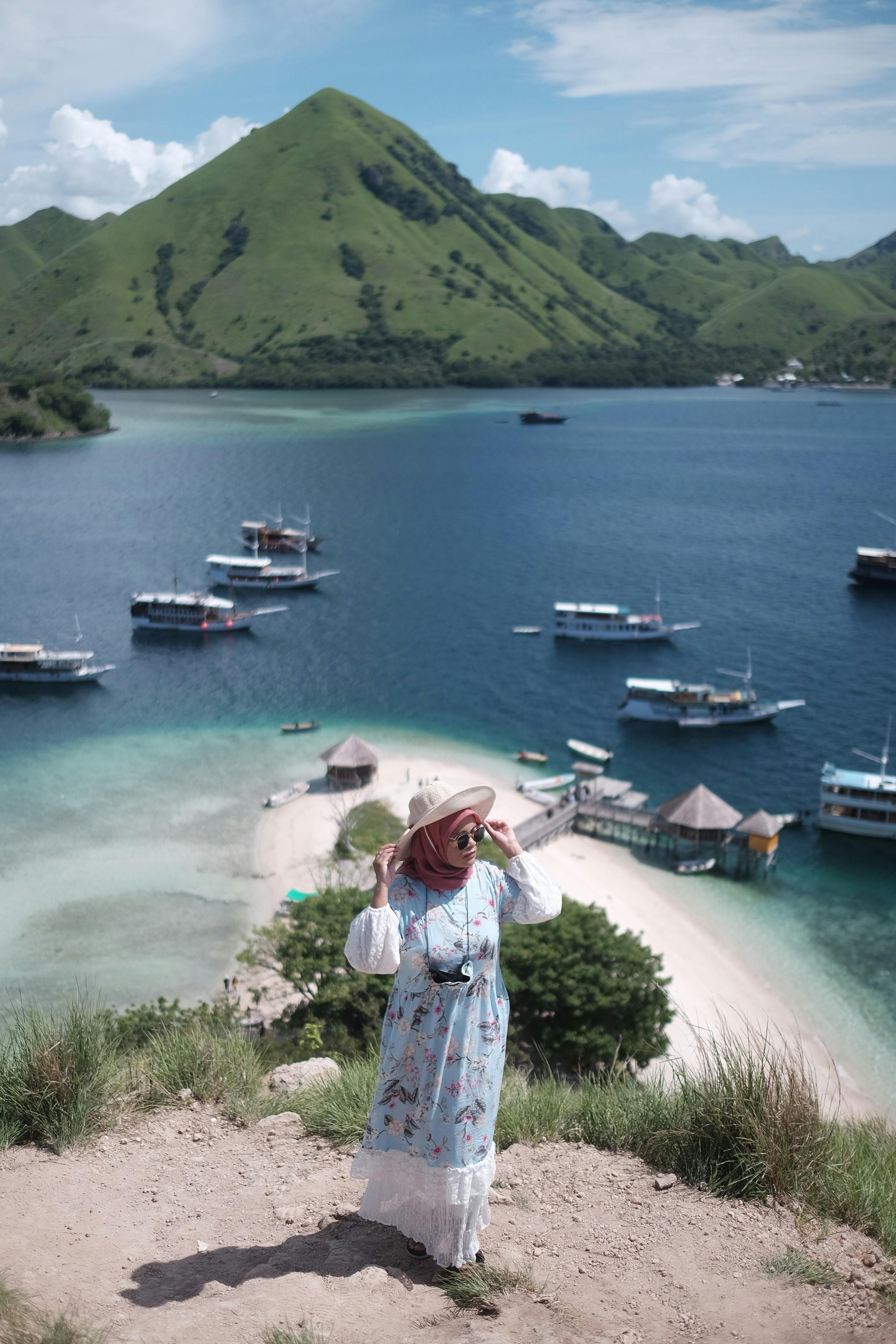 Tourist overlooking Pulau Kelor, East Nusa Tenggara, with lush hills and sea in the background.