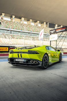 A vibrant green Lamborghini Huracan parked at a professional racing track pit area, showcasing sleek design and powerful performance.