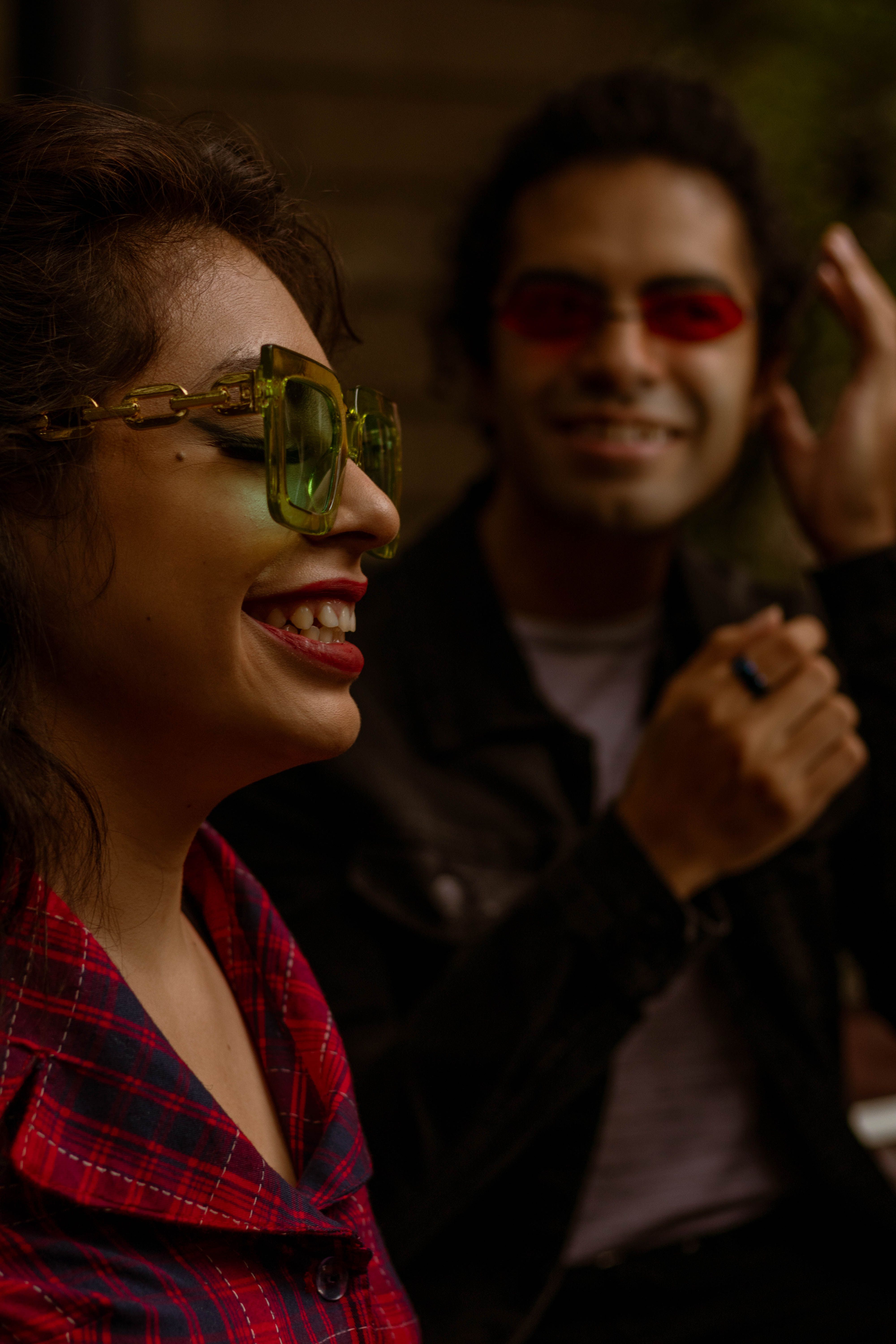 Two adults wearing stylish sunglasses and plaid shirts enjoying a day out.