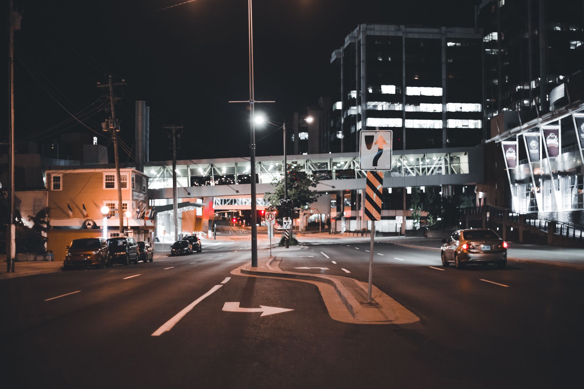City street at night with modern buildings and car lights illuminating the scene.