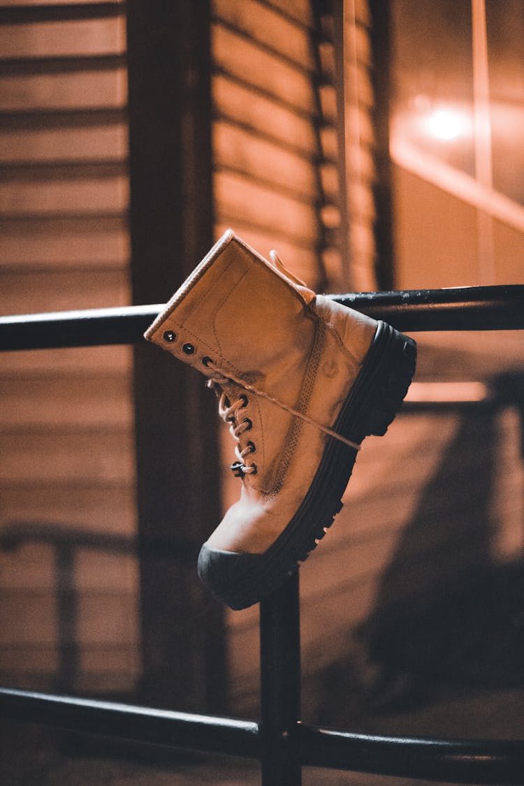 Brown Hiking Boot Hanging On Black Grill