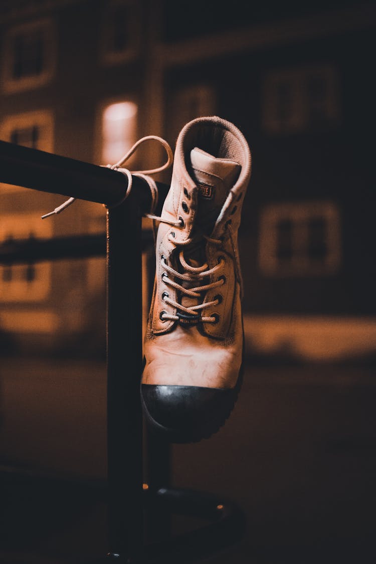 Brown Hiking Boot Hanging On Black Grill