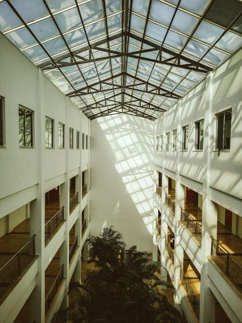 Free Spacious atrium with glass ceiling, symmetrical balconies, and natural light creating geometric patterns. Stock Photo