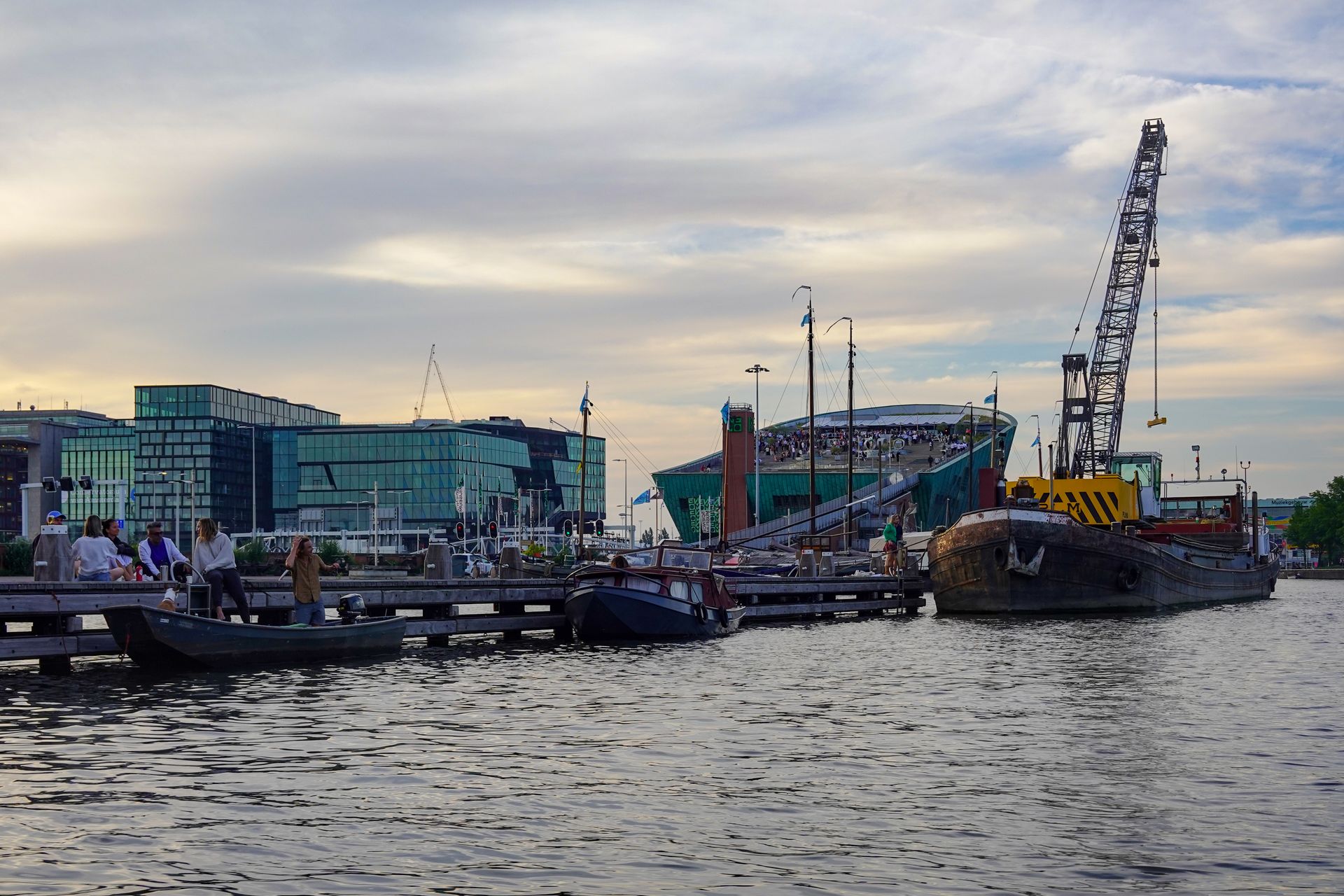 Beautiful Amsterdam waterfront featuring Nemo Science Museum, boats, and modern architecture at twilight.
