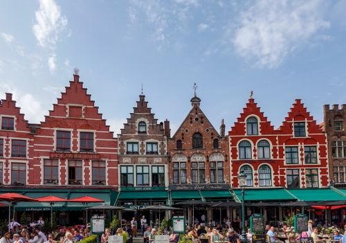 Charming gabled townhouses in Bruges Market Square, showcasing vibrant architecture and bustling atmosphere.