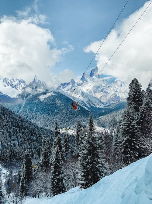 Person Riding Cable Car over Snow Covered Mountain