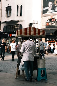 A street vendor in Istanbul sells snacks as people walk by on a busy day.