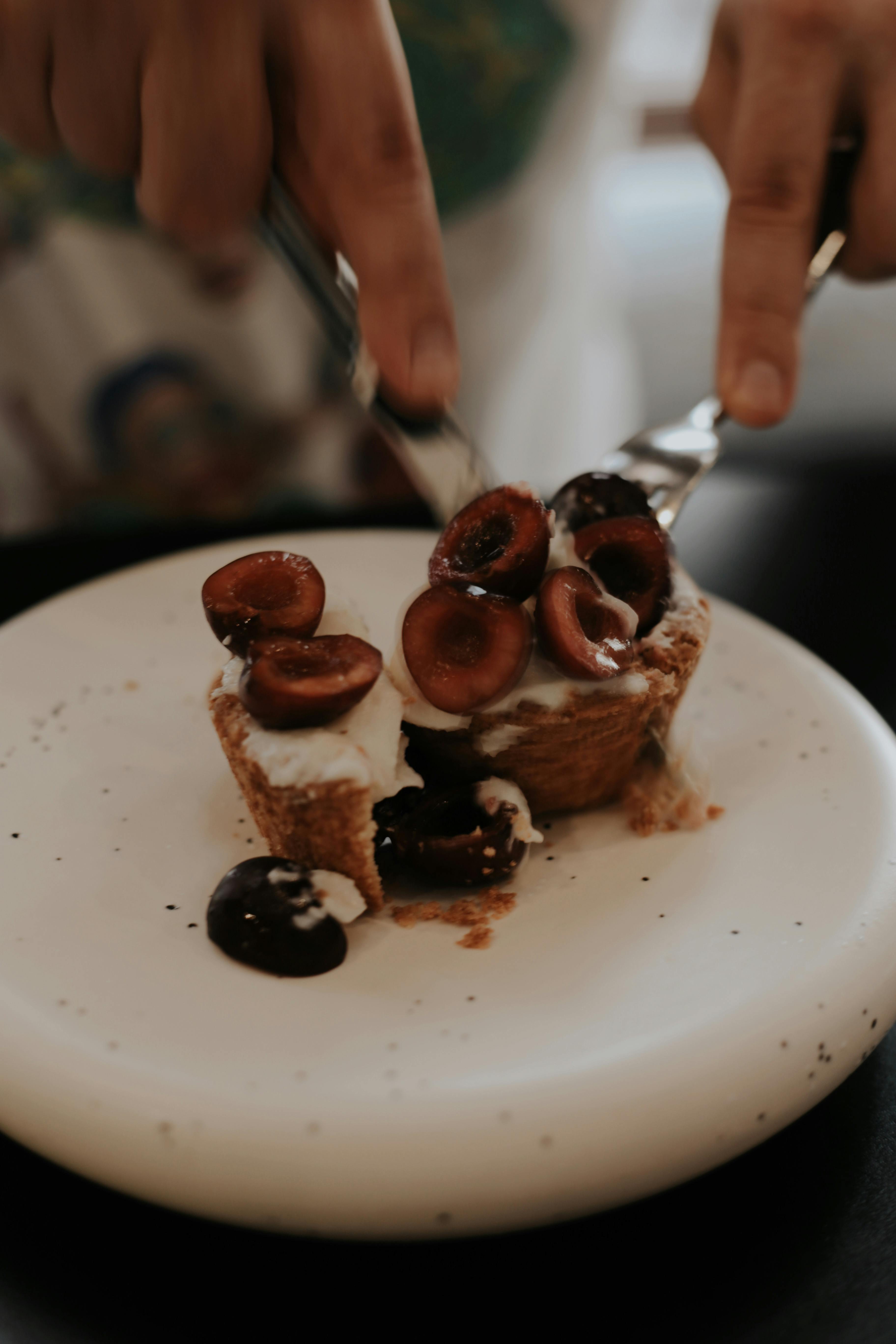 Hands cutting a delicious cherry tart, showcasing fresh fruit and creamy topping, perfect for dessert inspiration.