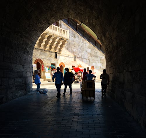 People Walking on an Arched Narrow Alley